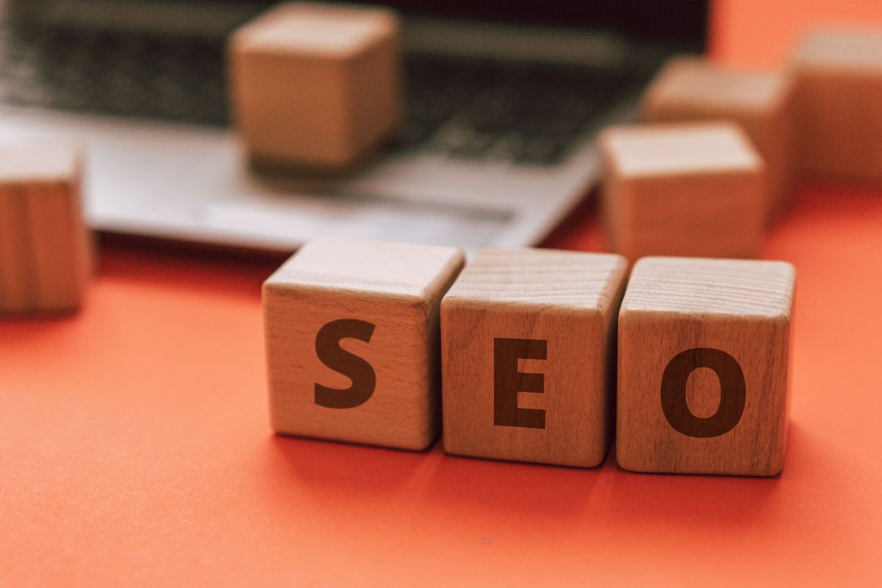Wooden blocks that spell SEO on a laptop keyboard illustrate digital marketing concepts.