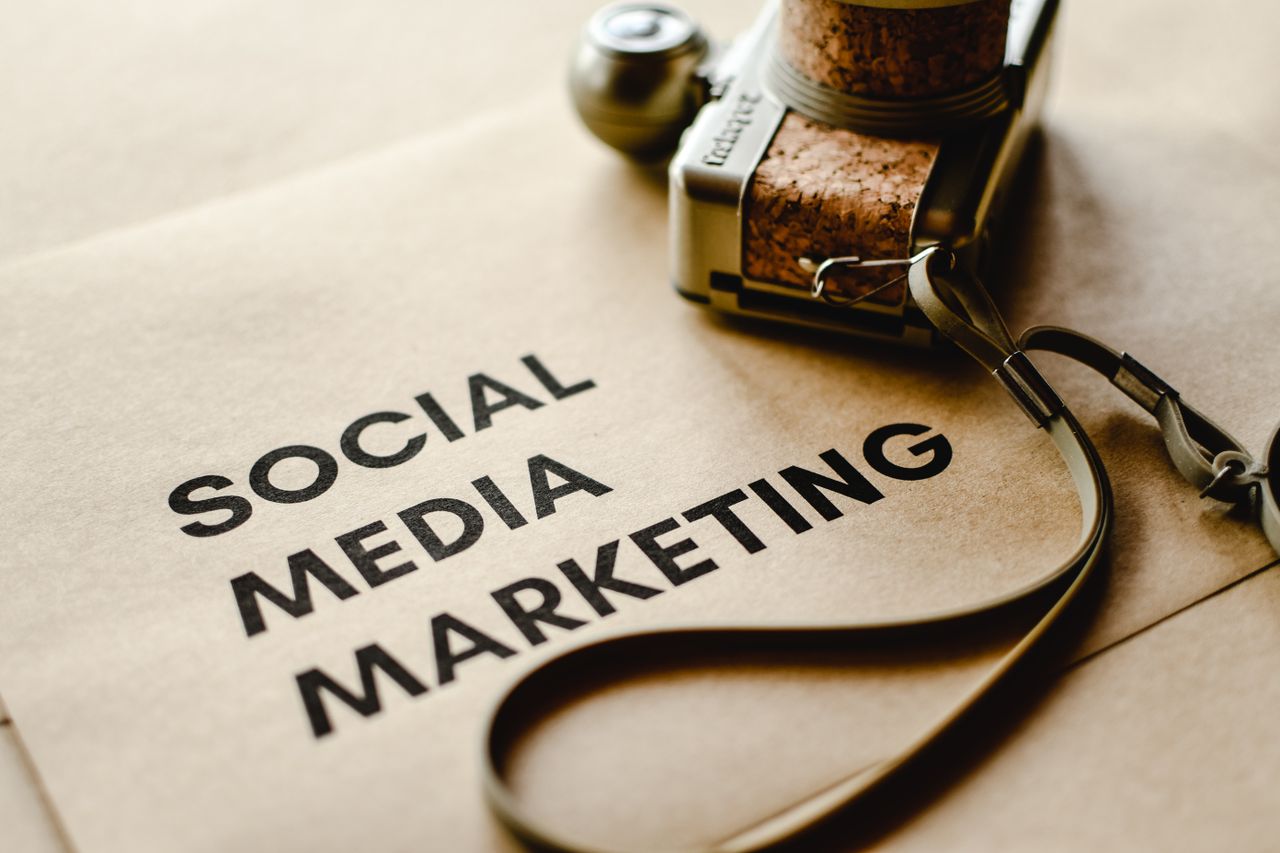 Vue rapprochée d’un appareil photo posé sur du papier brun, avec le texte Social Media Marketing, mettant en avant les thèmes du marketing digital.